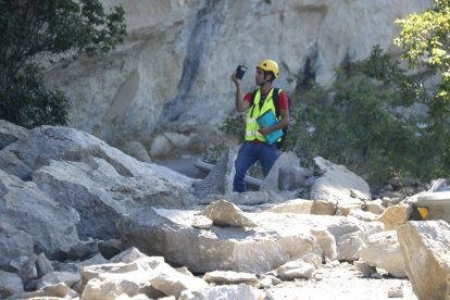 Un técnico de la empresa contratada por el consistorio, ayer entre las rocas caídas sobre la calzada.