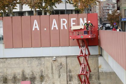 Operarios tapando ayer las grandes letras del rótulo de “A.Areny” de la pasarela de los Maristes.