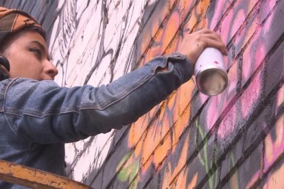 Una artista pintant un mural al festival GarGar de Penelles.