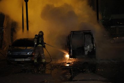 Un bombero apagando las llamas de la furgoneta que se calcinó.