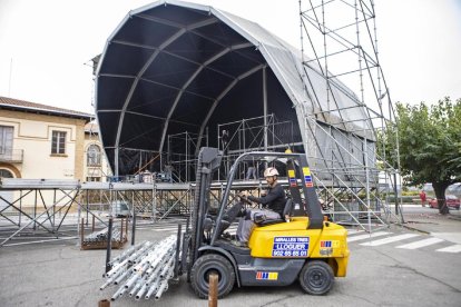 Un operario montado en un toro de transporte ayer durante el montaje de la gran carpa, al fondo.