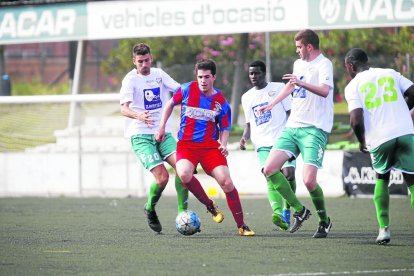 Un jugador del equipo visitante intenta controlar el balón ante la presión de los locales.