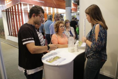 Visitants proven llet de cabra en un estand.