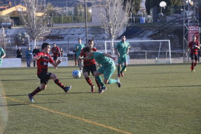 Un jugador del EFAC Almacelles pugna con uno del Martinenc, con varios jugadores de ambos equipos al fondo.