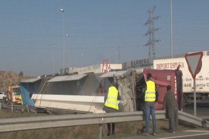 El camió, bolcat a la rotonda d'entrada a la ciutat de Lleida pel barri dels Magraners.