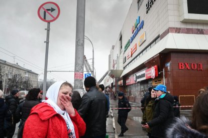 Una dona plora als voltants del centre comercial sinistrat.