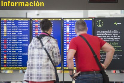 Pasajeros observando un panel de salidas en El Prat.