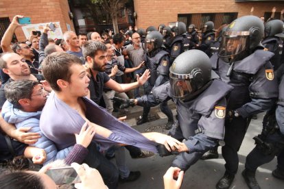 Un policía carga contra un joven ante el colegio de la Mariola. 