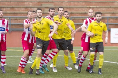 Jugadors dels dos conjunts pugnen per rematar una pilota aèria.