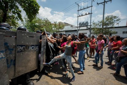 Un grup de familiars de presos protesta davant de membres de la policia.