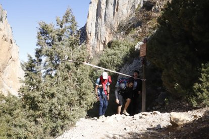 Excursionistas pasando ayer por debajo de una cinta para restringir el paso a una zona afectada por aludes en Mont-rebei.