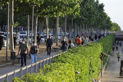 Paseantes por la calle Jaume II mientras los deportistas corren por la canalización