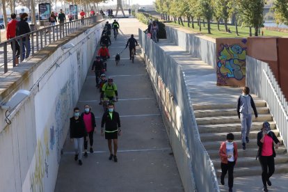 Un dels accessos a la canalització del riu Segre a Lleida, amb ciclistes i passejants, ahir.