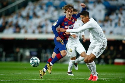 El blaugrana Antoine Griezmann intenta escapar-se de la pressió del seu compatriota Raphael Varane.