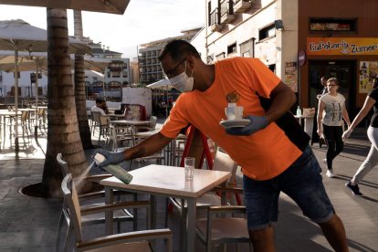 Un camarero desinfecta una mesa de este bar en Tenerife.