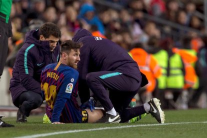 Leo Messi és atès a la banda durant el partit de dissabte contra el València.