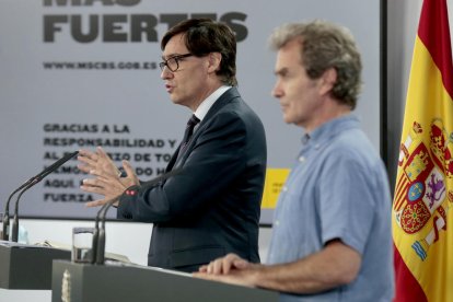 El director de CCAES, Fernando Simón, y del ministro de Sanidad, Salvador Illa, en un segundo término, en rueda de prensa.