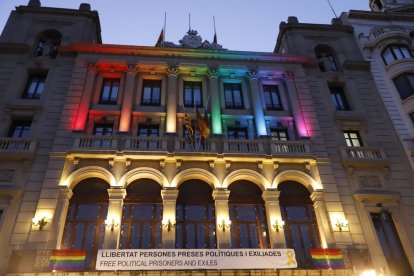 Bandera multicolor al balcó de l’ajuntament de les Borges i façana de la Paeria de Lleida il·luminada amb els colors de l’arc de Sant Martí.