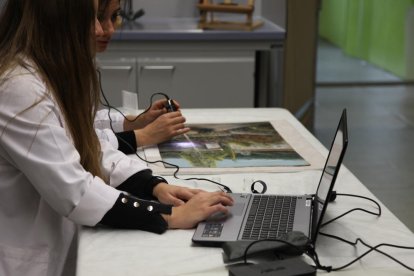 Dos investigadoras del CAEM, Mariona Navarro y Jessica Martí, examinando la textura de la pintura.