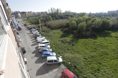 Imagen de la calle Marimunt, sin aceras y con varios coches aparcados junto a un solar con basuras. 