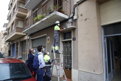 Un operari retira la placa franquista d’un bloc de Sant Jaume davant la mirada de Postius i Pueyo.