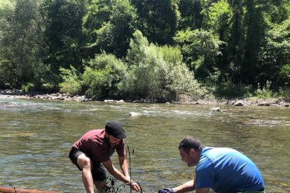 Dos vecinos construyendo el ‘rai’ que hoy descenderá por el río Noguera Pallaresa. 