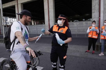 Membres de Protecció Civil reparteixen mascaretes en una estació de Còrdova.