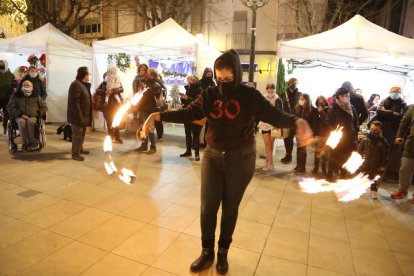 Espectáculo de fuego ayer en el mercado navideño de Mollerussa. A la derecha, una de las paradas con motivos navideños en el Mercat de Santa Llúcia de Lleida. 