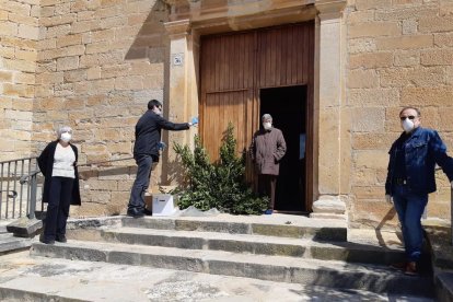 El capellà i veïns de Preixana amb mascaretes aquest diumenge durant la benedicció de rams.