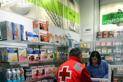 Un voluntario de Cruz Roja recogiendo un medicamento en una farmacia de Lleida para llevárselo a un enfermo.