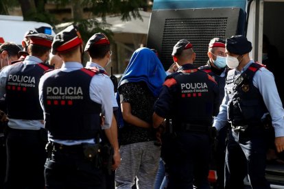 Els Mossos d’Esquadra condueixen cap al furgó un dels detinguts en el macrooperatiu.