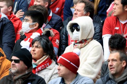 Aficionados viendo ayer el Liverpool-Bournemouth con mascarillas por temor al coronavirus.