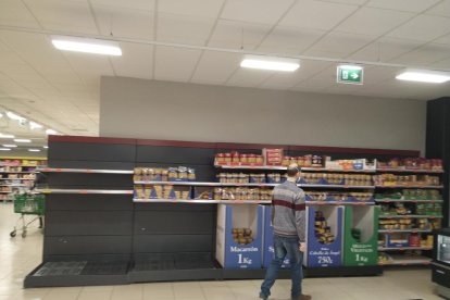 Ciutadans fan cua mantenint la distància de seguretat davant d’un supermercat al centre urbà.