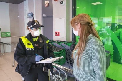 Una policia local de Mollerussa controla l’entrada a un súper.