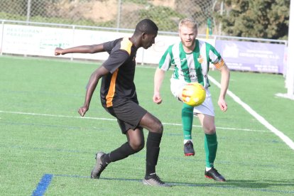 Un jugador del Alguaire intenta controlar el balón ante un defensa del Pinyana.