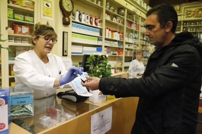 Un hombre recoge la  mascarilla con la tarjeta sanitaria.