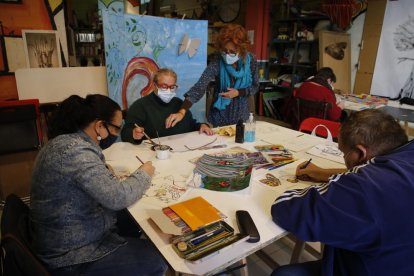 Rosa Franco, de l’Escola Traç de Lleida, amb usuaris del club social La Brúixola en un taller d’art.