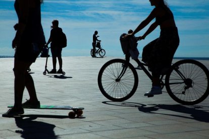 Diverses persones amb bicicleta i patinets a la platja de la Barceloneta durant la desescalada