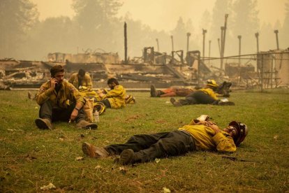 Bomberos tomando un descanso frente a una escuela devastada.