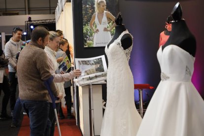 Visitantes  se interesan por los catálogos de vestidos de novia de uno de los expositores de la feria. 