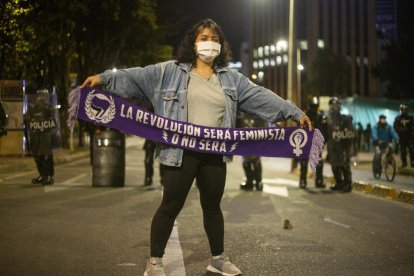 Una manifestant passa davant d’un cordó policial durant els disturbis a Bogotà.