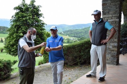 Un treballador de l’Aravell Golf procedeix a aplicar gel desinfectant a les mans d’un jugador mentre un altre espera el seu torn.