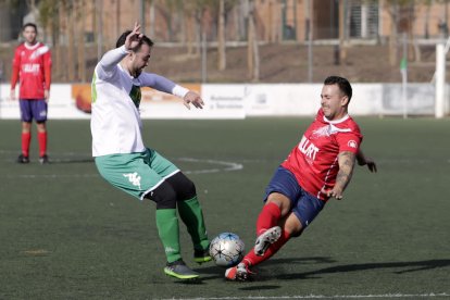 Un jugador del equipo local y uno del visitante se disputan por el balón.