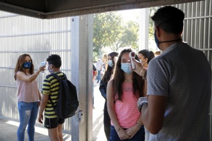 Professors de l’institut Gili i Gaya prenen la temperatura als alumnes en l’accés al centre.