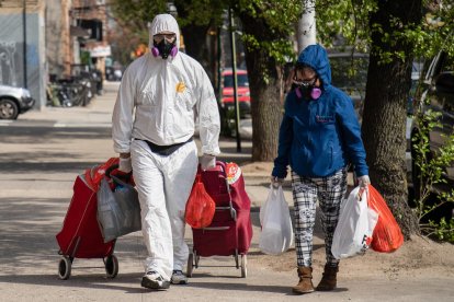 Dos persones a Nova York amb mesures de protecció després d’anar a comprar el supermercat.