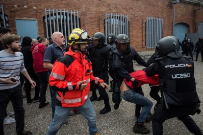 Policías nacionales cargan en un colegio electoral de Girona el 1-O en presencia de un bombero.