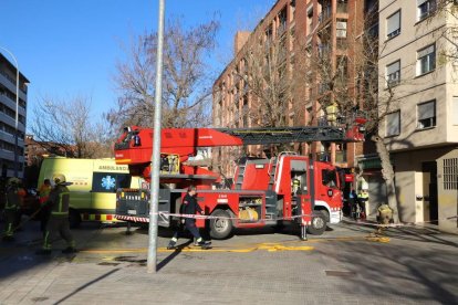 Els bombers, amb el camió escala, al primer pis de l'edifici de Pardinyes on s'ha originat un incendi.