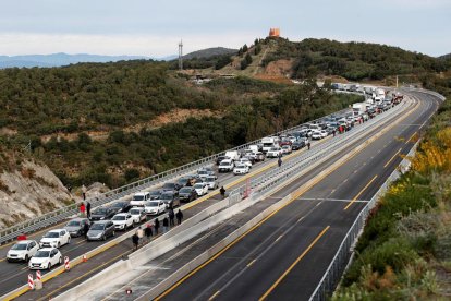 Camiones y coches bloqueados en La Jonquera, y manifestantes caminando por la vía, ayer.