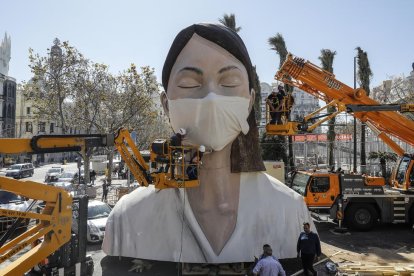 Ponen una mascarilla a una figura tras el aplazamiento de las Fallas.