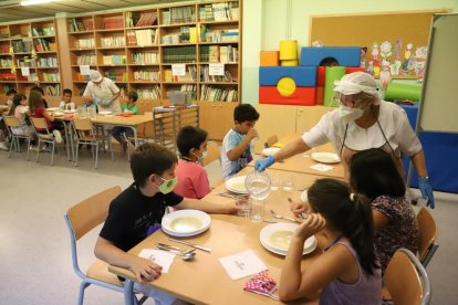 Una monitora serveix aigua als alumnes del Frederic Godàs, que han de dinar a la biblioteca.